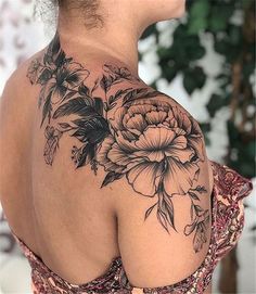 the back of a woman's shoulder with flowers and leaves on her left arm