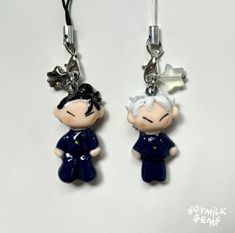 two key chains with small cartoon characters attached to them, one is wearing a blue dress and the other has a white hair