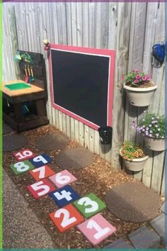 an outdoor play area with letters and numbers on the ground in front of a fence