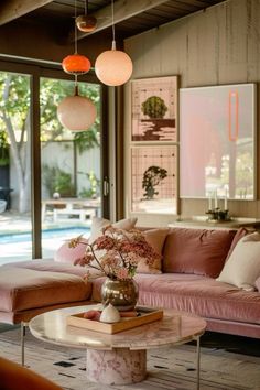 a living room with couches, tables and lamps hanging from the ceiling in front of a swimming pool