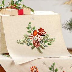 a christmas present wrapped in white paper with holly and pine cones