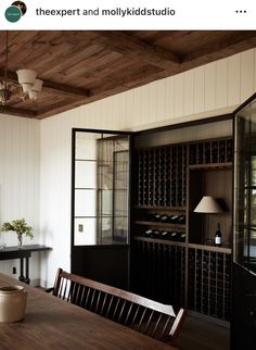 a dining room table with wine bottles on it and a chandelier hanging from the ceiling