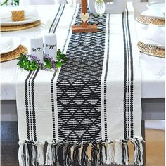 the table is set with white and black place mats, napkins, candles, and flowers