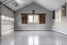 an empty garage with basketball hoop in the middle and two windows on each side that are open