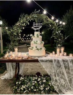 a wedding cake sitting on top of a wooden table covered in flowers and greenery