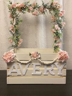 a wooden sign that says avery with flowers on it