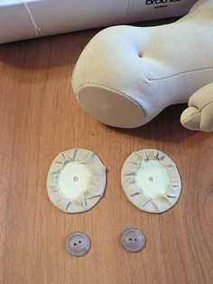 a stuffed animal sitting next to two buttons and a pair of scissors on top of a wooden table