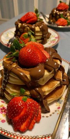 a stack of pancakes covered in chocolate and strawberries