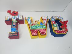 three wooden letters with sesame street characters on them