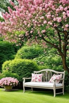 a bench sitting in the middle of a lush green field with pink flowers on it