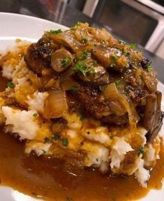 a white plate topped with mashed potatoes covered in gravy and mushroom sauce