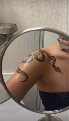 a woman's arm with snake tattoos on it in front of a mirror,