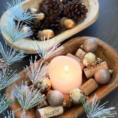 a candle and some wine corks in a bowl with pine cones on the side