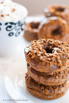 three chocolate donuts stacked on top of each other next to a cup of coffee