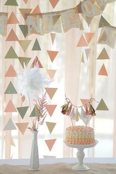 there is a cake on the table with flowers in vases and bunting streamers