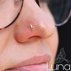 a close up of a person wearing glasses with a nose pin in the middle of their nose