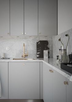 a kitchen with white cabinets and marble counter tops, gold faucet pulls on the cabinet doors