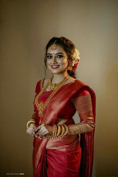 a woman wearing a red sari and gold jewelry