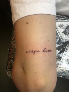 a woman with a small tattoo on her leg that says carpe diem in cursive writing