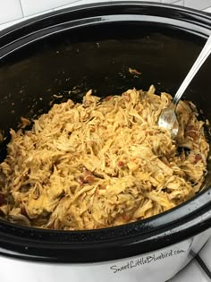 a slow cooker filled with shredded food and a spoon in the crock pot