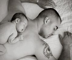 a man laying on top of a bed next to a sleeping baby in his arms