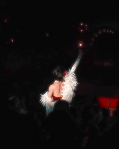 a woman with white feathers on her body in front of a crowd at a concert