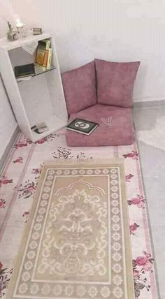 a living room with a pink chair and rug on the floor next to a book shelf