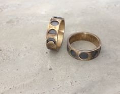 two rings sitting on the ground next to each other, one with black stones in it