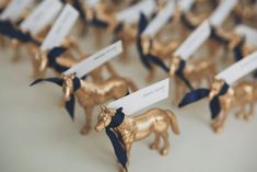 small gold horse figurines with name tags on them are lined up in rows