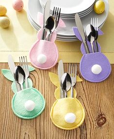 four bunny napkins with forks and spoons on a table next to an easter egg