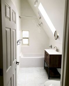 a bathroom with a toilet, sink and bathtub under a slanted skylight