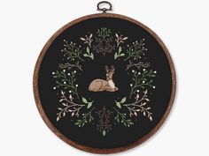 a cross stitch pattern with an image of a deer in the center and foliage around it