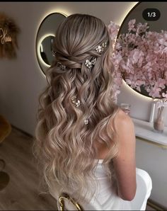 a woman sitting in front of a mirror with her hair styled into a half - updo