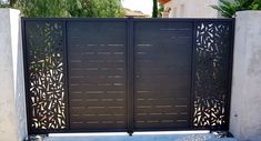 an iron gate with decorative designs on the top and bottom part, in front of a house