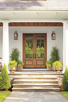 the front entrance to a house with two large doors and three planters on either side