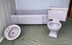 a white toilet sitting next to a bath tub in a bathroom under a tarp