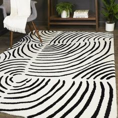 a black and white area rug in a living room with a chair, potted plant and bookshelf