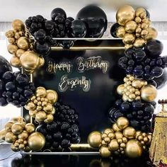 a black and gold birthday party with balloons in the shape of an arch that says happy birthday