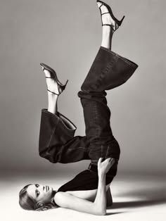 a woman laying on the ground with her legs up in the air while wearing high heels