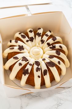 a cake in a box with white icing and chocolate chips on it's side