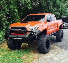 an orange truck is parked in front of some trees