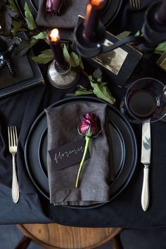 a black table setting with flowers and candles