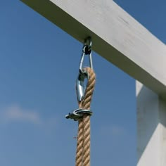 a rope hanging from the side of a wooden structure with blue skies in the background