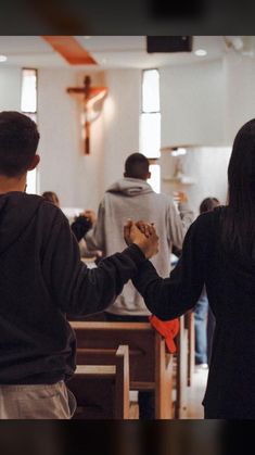 two people holding hands while standing in front of pews