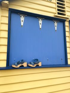 blue and yellow building with two pairs of shoes on the window sill