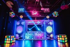 a stage set up for a party with colorful lights and sound cubes on the floor