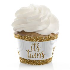 a cupcake with white frosting and gold sprinkles that says it's twins