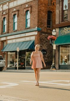 a woman walking across a street in front of a store