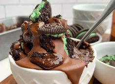 a bowl filled with chocolate and oreo cookies on top of a wooden table next to bowls