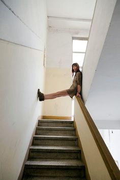 a woman leaning on the edge of a set of stairs with her leg up and legs down